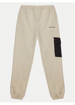 Calvin Klein Jeans Spodnie dresowe IB0IB02349 Écru Relaxed Fit ze sklepu MODIVO w kategorii Spodnie chłopięce - zdjęcie 182684464
