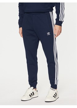 adidas Spodnie dresowe adicolor 3-Stripes IM9319 Granatowy Slim Fit ze sklepu MODIVO w kategorii Spodnie męskie - zdjęcie 182688341