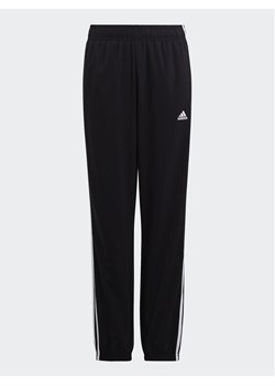 adidas Spodnie dresowe Essentials 3-Stripes Woven Tracksuit Bottoms HR6334 Czarny Slim Fit ze sklepu MODIVO w kategorii Spodnie chłopięce - zdjęcie 182731894