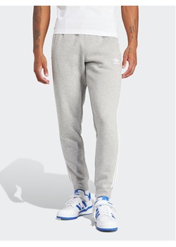 adidas Spodnie dresowe adicolor 3-Stripes IM9318 Szary Slim Fit ze sklepu MODIVO w kategorii Spodnie męskie - zdjęcie 182732704