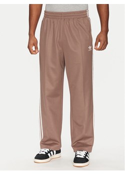 adidas Spodnie dresowe adicolor Firebird JP1067 Beżowy Baggy Fit ze sklepu MODIVO w kategorii Spodnie męskie - zdjęcie 182737712