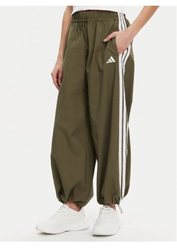 adidas Spodnie dresowe Essentials 3-Stripes JE1308 Zielony Loose Fit ze sklepu MODIVO w kategorii Spodnie damskie - zdjęcie 182742450