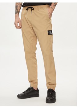 Calvin Klein Jeans Joggery Monologo Badge J30J325114 Beżowy Skinny Fit ze sklepu MODIVO w kategorii Spodnie męskie - zdjęcie 182763604