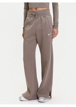 Nike Spodnie dresowe Phoenix DQ5615 Brązowy Regular Fit ze sklepu MODIVO w kategorii Spodnie damskie - zdjęcie 183620250