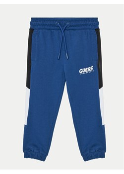 Guess Spodnie dresowe N5RQ11 KA6R4 Niebieski Relaxed Fit ze sklepu MODIVO w kategorii Spodnie chłopięce - zdjęcie 184045632