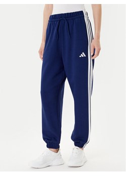 adidas Spodnie dresowe Essentials 3-Stripes Fleece JX7696 Niebieski Loose Fit ze sklepu MODIVO w kategorii Spodnie damskie - zdjęcie 185040814