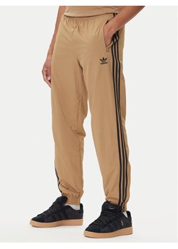 adidas Spodnie dresowe adicolor Woven Firebird JY1339 Beżowy Regular Fit ze sklepu MODIVO w kategorii Spodnie męskie - zdjęcie 185415911