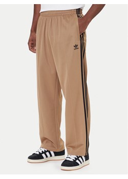 adidas Spodnie dresowe adicolor Firebird JY1419 Beżowy Baggy Fit ze sklepu MODIVO w kategorii Spodnie męskie - zdjęcie 186569884