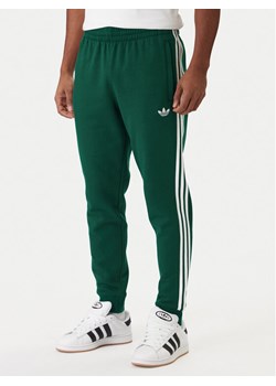 adidas Spodnie dresowe 3-Stripes KE3559 Zielony Slim Fit ze sklepu MODIVO w kategorii Spodnie męskie - zdjęcie 187971173