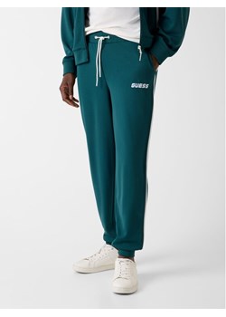 Guess Spodnie materiałowe 180419 Zielony Regular Fit ze sklepu MODIVO w kategorii Spodnie męskie - zdjęcie 188020530