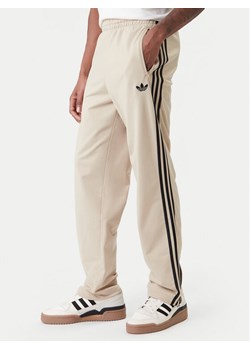 adidas Spodnie dresowe Firebird KE6679 Beżowy Loose Fit ze sklepu MODIVO w kategorii Spodnie męskie - zdjęcie 188070321