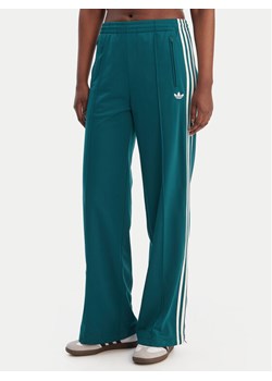 adidas Spodnie dresowe Firebird KG3701 Zielony Loose Fit ze sklepu MODIVO w kategorii Spodnie damskie - zdjęcie 188109063