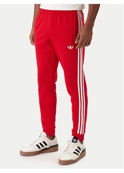 adidas Spodnie dresowe 3-Stripes KE3560 Czerwony Slim Fit ze sklepu MODIVO w kategorii Spodnie męskie - zdjęcie 188122624