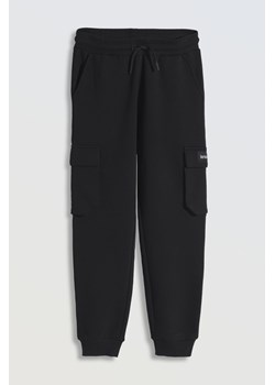 Czarne spodnie dresowe oversize z przestrzennymi kieszeniami na nogawkach, Rozmiar - 140, Kolor - Czarny ze sklepu REPORTER w kategorii Spodnie chłopięce - zdjęcie 189106714
