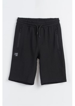 Czarne krótkie spodenki dresowe REGULAR z naszywką, Rozmiar - 140, Kolor - Czarny ze sklepu REPORTER w kategorii Spodenki chłopięce - zdjęcie 189106770