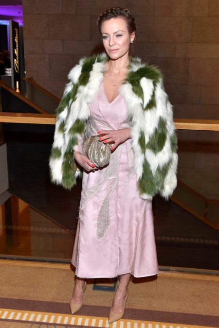 Magdalena Boczarska w satynowej, różowej sukience wieczorowej i z narzuconym na ramiona futerkiem we wzory.